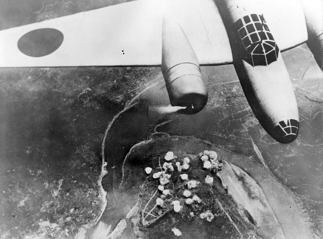 A Japanese Ki-21 bomber photographed from above, flying over the Chongqing peninsula with smoke rising from the city.