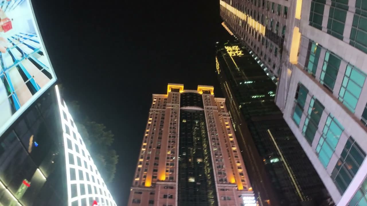 Looking straight up at the towers around Jiefangbei at night, their floor plates lit.